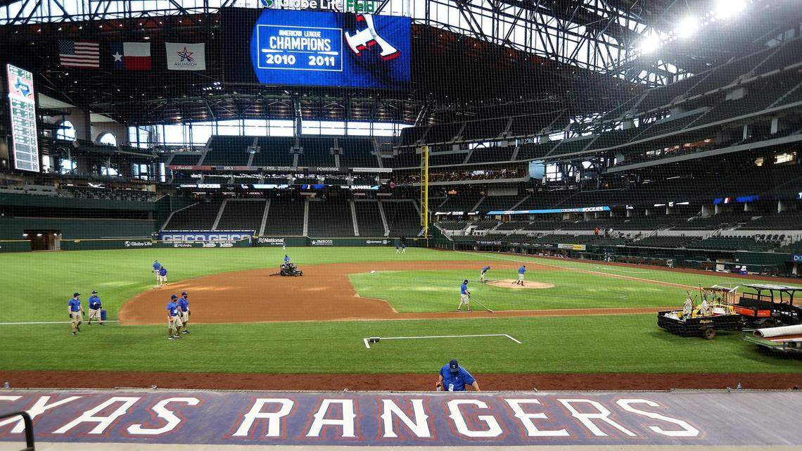 Globe Life Field staff prepares the field for Wednesday’s exhibition game, and after a four-month delay the Texas Rangers will open their new ballpark and season on Friday night against the Colorado Rockies.