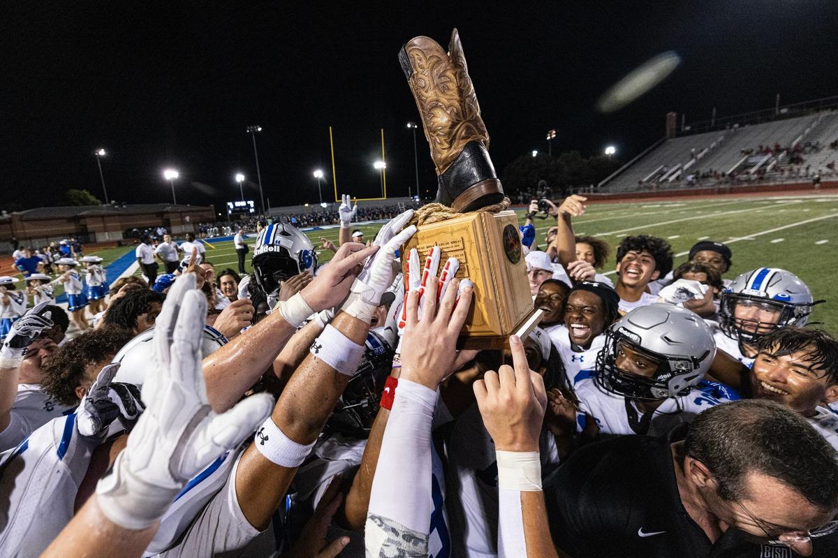 The Burleson Centennial Spartans football team hoists the Boot Bowl trophy after winning the 2024 Boot Bowl game against Burleson High School at BISD Stadium in Burleson on Friday, Aug. 30, 2024. The Spartans defeated the Elk 28-7 to take home the Boot Bowl trophy for the third year in a row.