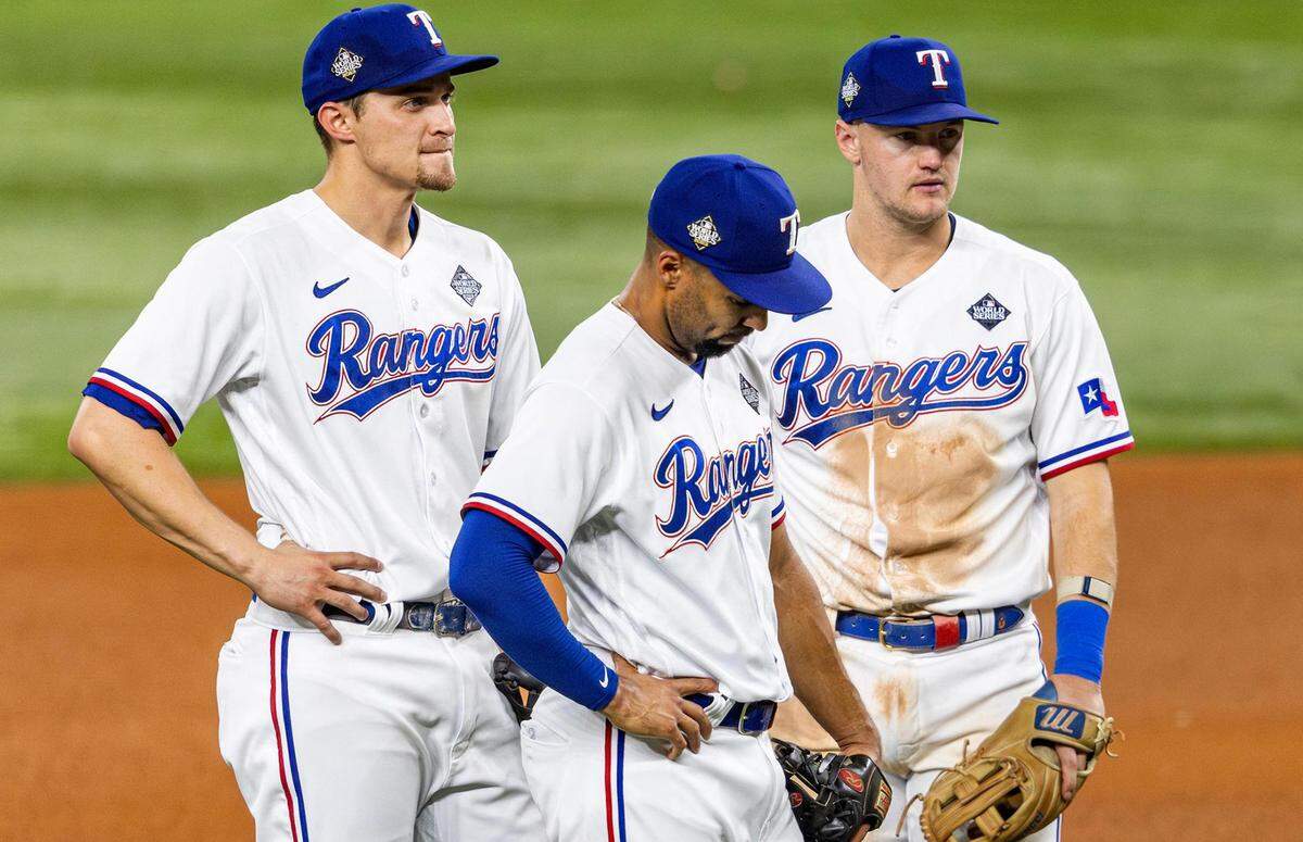Texas Rangers second baseman Marcus Semien, center, reacts during the seventh inning with teammates Corey Seager, left, and Josh Jung during Game 2 of the World Series against the Arizona Diamondbacks on Saturday at Globe Life Field in Arlington.