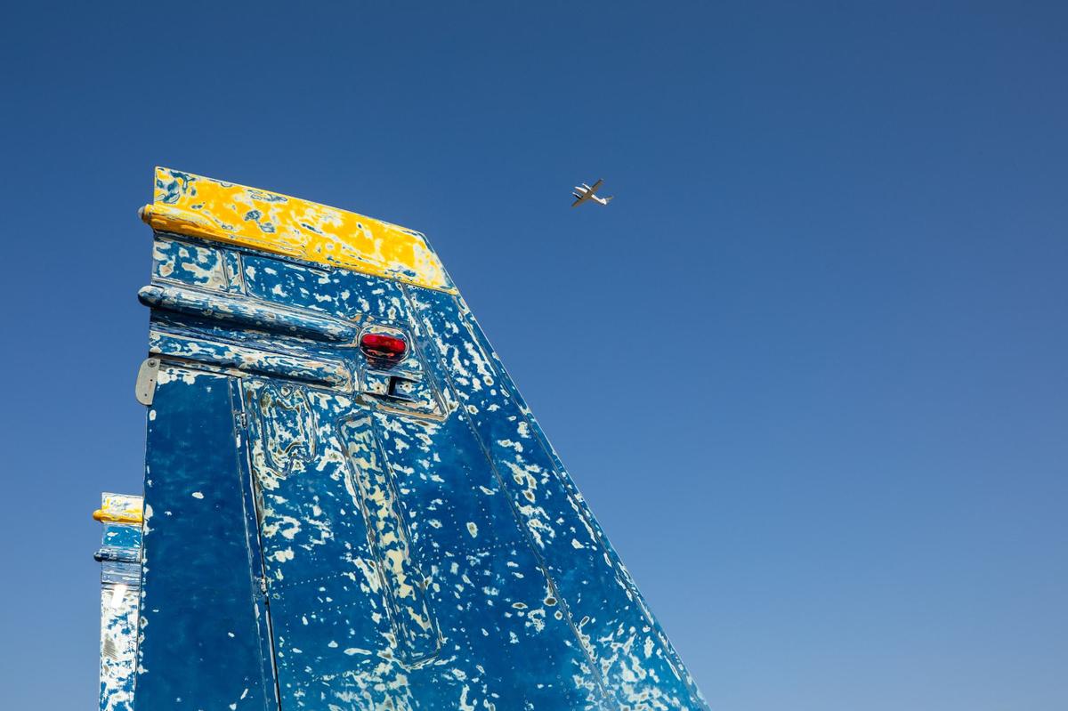 The tail wings of a F-18 Hornet used by the Blue Angels as a plane flies over head on Thursday, August 1, 2024 at the Fort Worth Aviation Museum. The museum is located at Fort Worth Meacham International Airport.