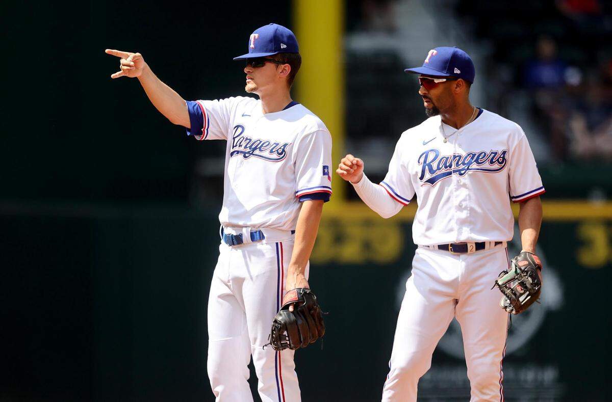 Texas Rangers shortstop Corey Seager, left, and second baseman Marcus Semien react after a close call against the Colorado Rockies on Monday, April 11, 2022, at Globe Life Field.