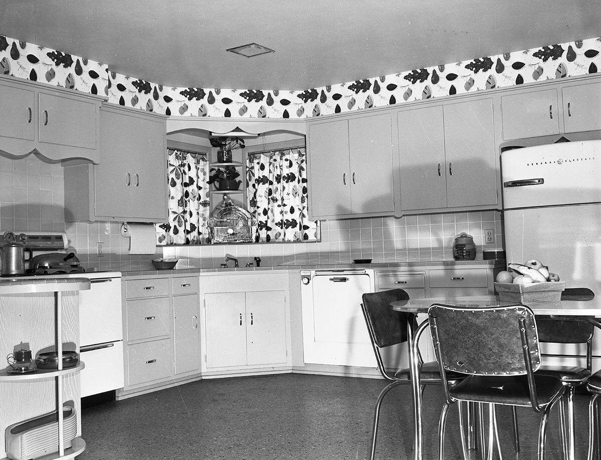 April 1954: A corner of the big kitchen at the home of Dewitt McKinleys at 6728 Fortune Road. The color theme is white and yellow with a splatter pattern linoleum covering. The breakfast table is shown at right.
