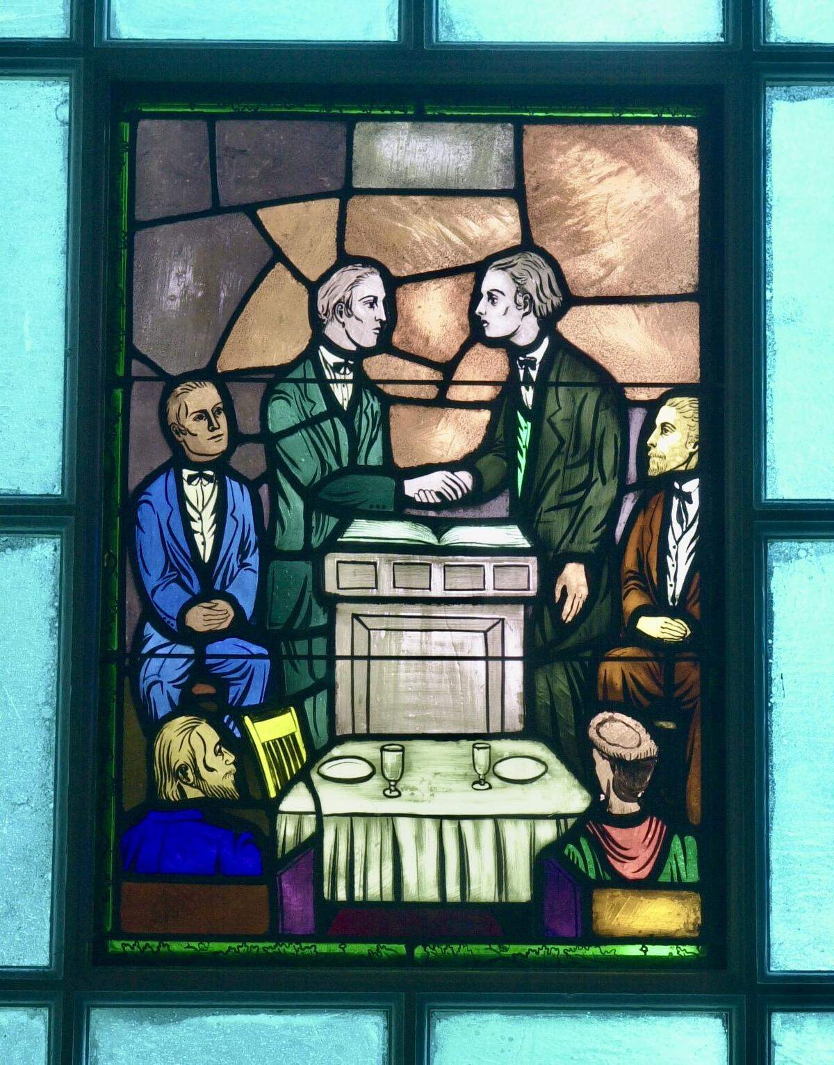 This stained glass, in a window of the stone structure surrounding the log Meeting House in Bourbon County, Kentucky, shows early Church of Christ leader Barton W. Stone and “Raccoon” John Smith shaking hands in union of the Stone-Campbell Reformation religious movements Jan. 1, 1832, at Lexington, Kentucky. The 200th anniversary of the Great Revival at Cane Ridge, which drew 30,000 people and spurred an evangelical movement, was celebrated in 2011 with “The Great Gathering” at the Cane Ridge Meeting House in Bourbon County.