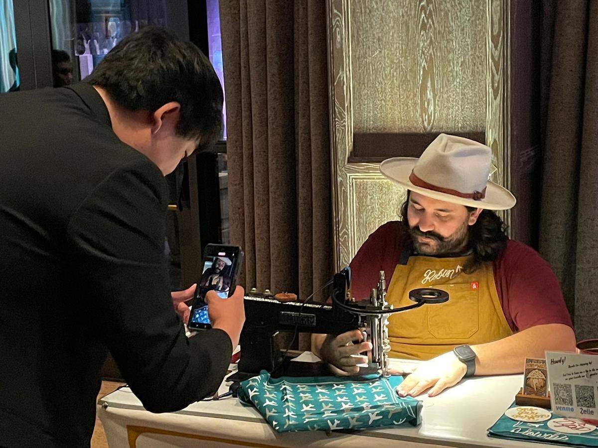 A guest watches a craftsman custom embroider a bandanna at Cathay Pacific’s launch party for its new flight from DFW at Bowie House on April 23, 2025.