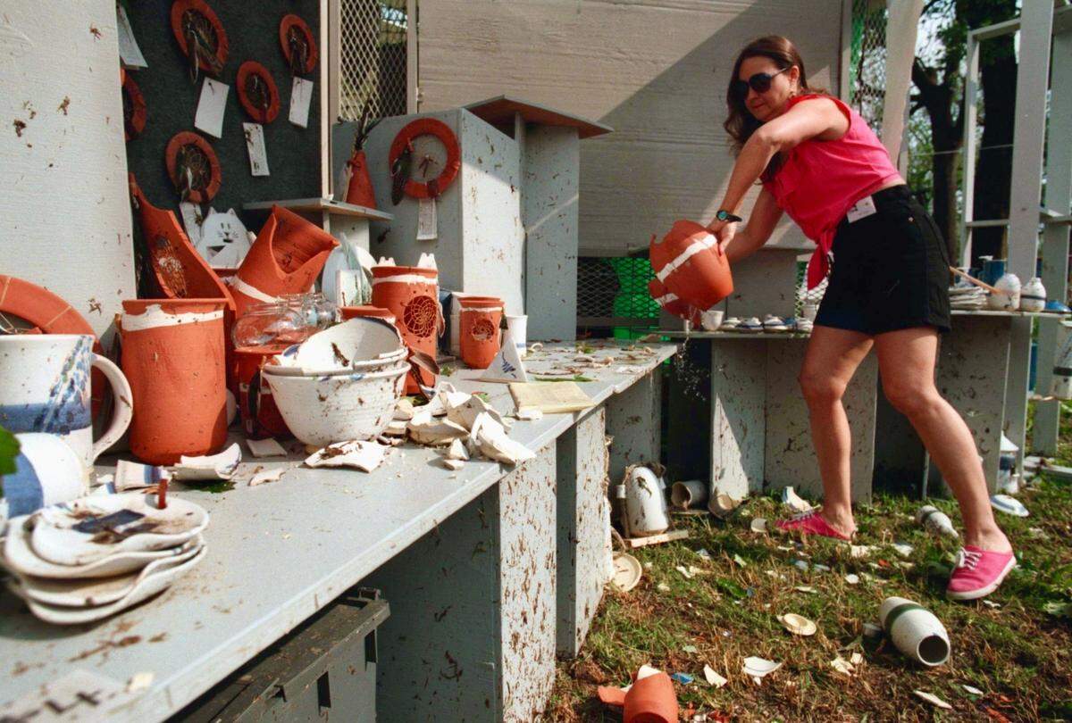 Patti Rhoades removes broken pieces of art made by her husband John from their booth at Mayfest in Trinity Park. May 6, 1995. (FWST/RON JENKINS)