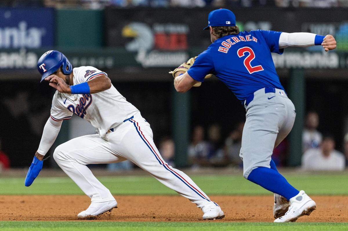 Texas Rangers first baseman Ezequiel Duran (20) attempts to avoid the tag from Chicago Cubs shortstop Nico Hoerner (2) in the fifth inning in their season opener at Globe Life Field in Arlington on Thursday, March 28, 2024.