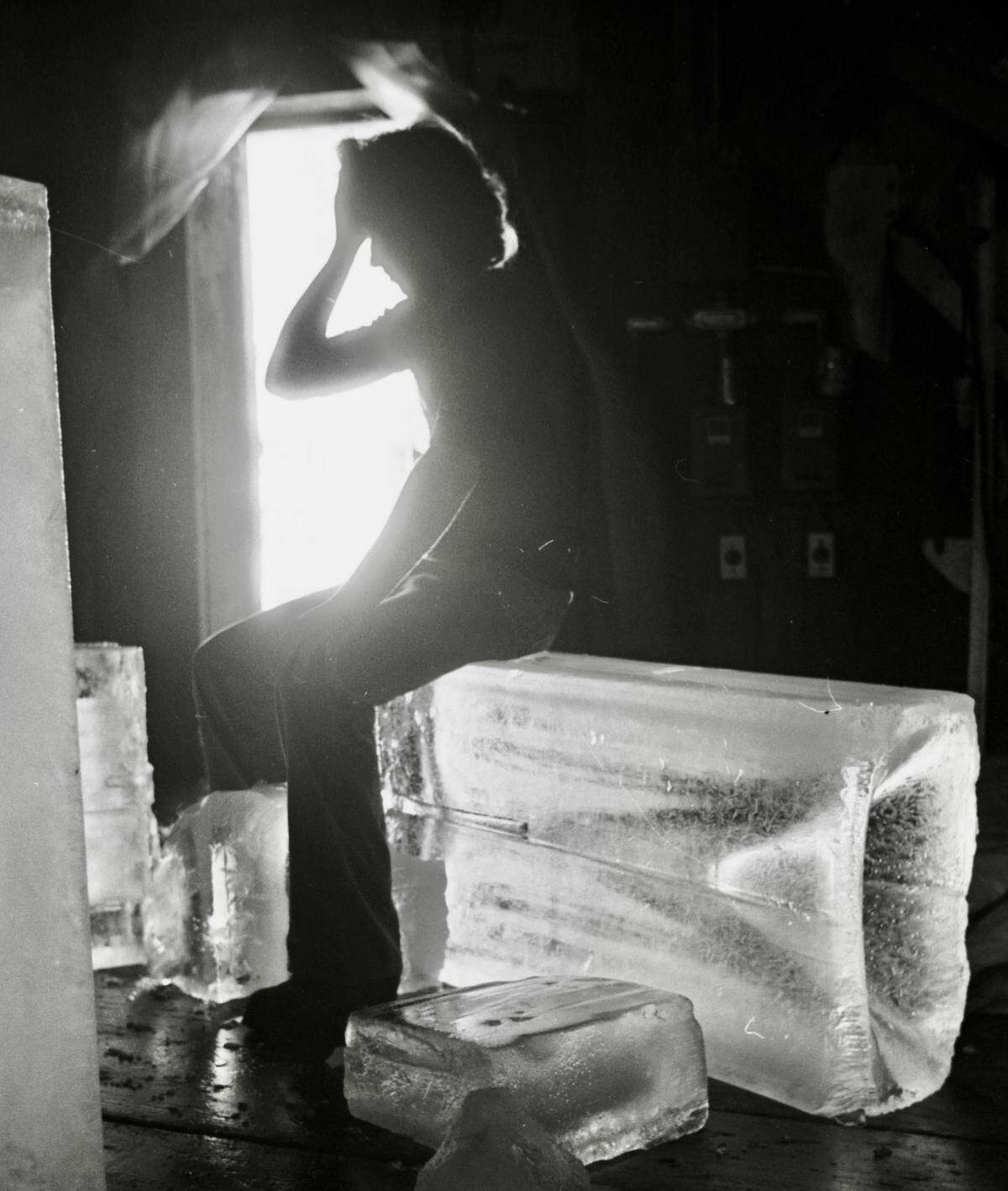  Crystal Ice Co. worker Van Russell, silhouetted, takes a break in the icehouse while working on a hot summer day in Fort Worth, Texas, June 27, 1980.