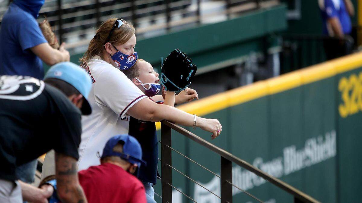 Courtney Pierce holds her son, Greyson, 4, during warmups before the Texas Rangers exhibition against the Milwaukee Brewers on Monday, March 29, 2021. Monday’s game was the first time that fans were able to attend a Rangers game at the new Globe Life Field in Arlington.