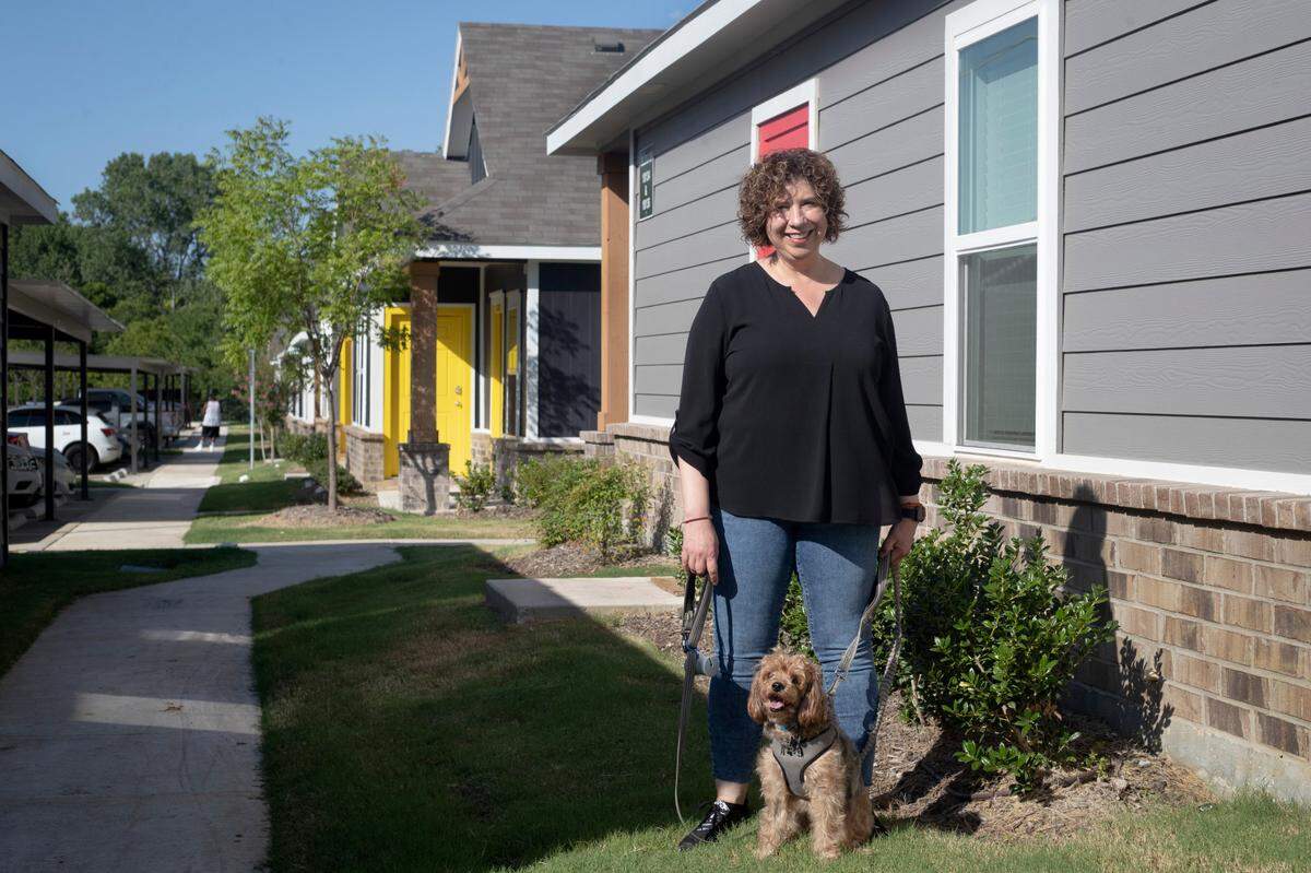 Maribel Romo and her dog Elvis go for a walk at the Cottages at Bell Station in Hurst, Texas, on July 5, 2022. Romo chose an apartment on the first floor specifically for Elvis’ needs.