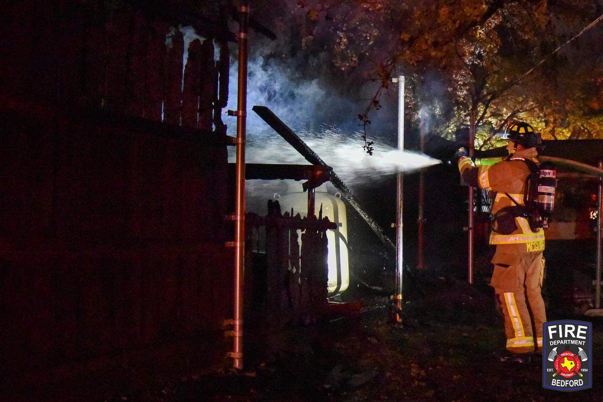 A firefighter shoots a stream of water into the smoldering ruins of a structure.