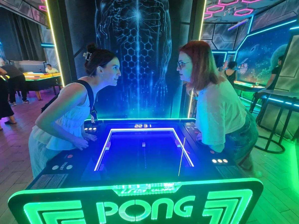 Reporter Ella Gonzales (left) and Kamilla Kosenko battle head-to-head during a game of virtual ping pong at an arcade in Krakow, Poland.