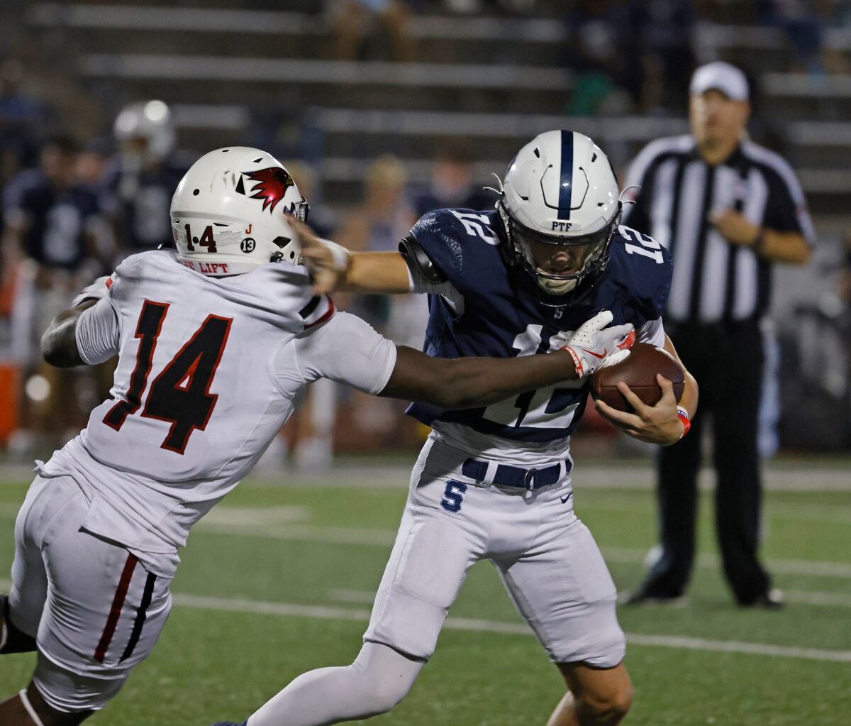 All Saints quarterback Jaxon Knapp (12) fends off Lift for Life Academy defensive end Isiah Jones (14) in the backfield at All Saints High School’s McNair Stadium in Fort Worth Thursday, Sept. 12, 2024.