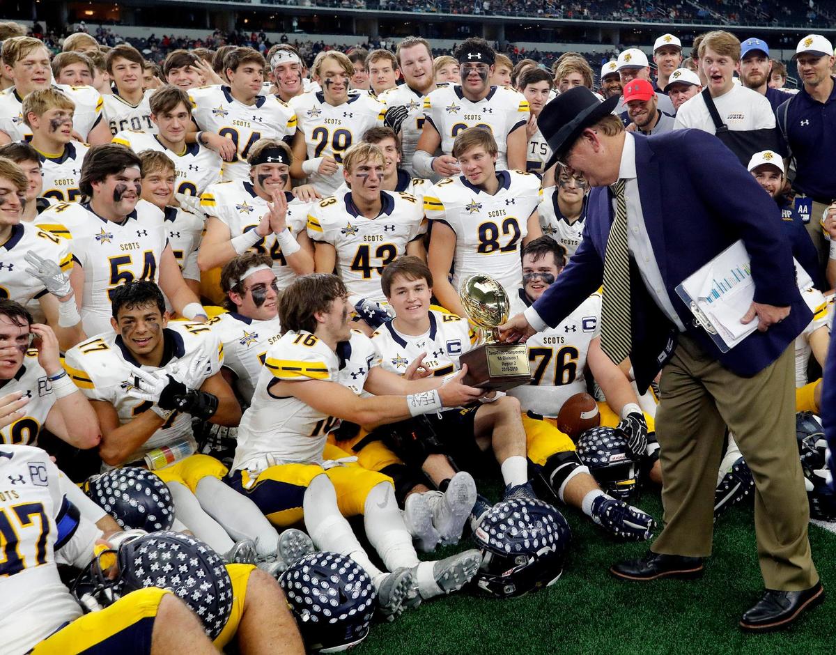 Highland Park head coach Randy Allen hands the trophy to wide receiver Finnegan Corwin (16) after they won a high school Class 5A Division I State Semifinals football playoff game at AT&T Stadium, Arlington, Texas, Saturday, Dec. 15, 2018. Highland Park won 43-21. (Star-Telegram Bob Booth)