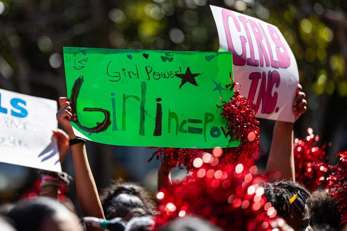 Posters are held up by members of the Girls Inc. of Tarrant County for the 2023 Day of the Girl march at Burnett Park in Fort Worth on Friday.