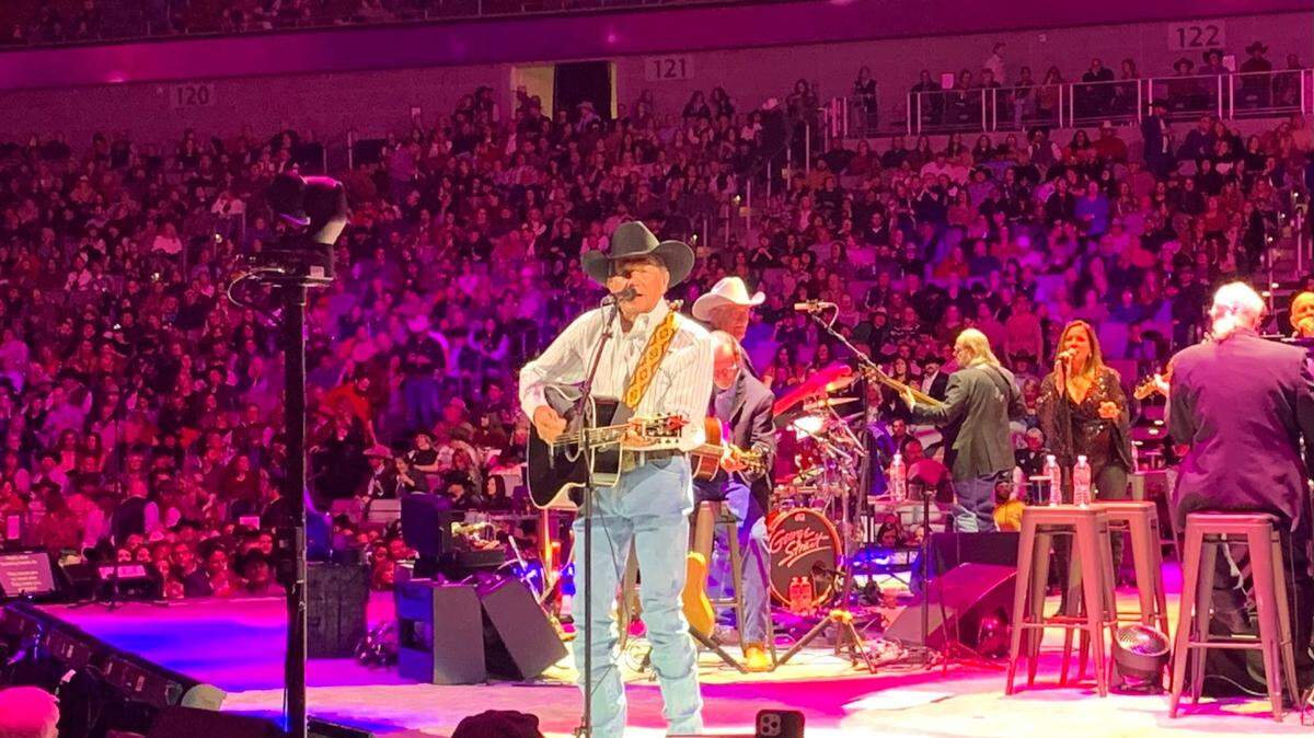 George Strait singing and strumming a guitar on stage at Dickies Arena.