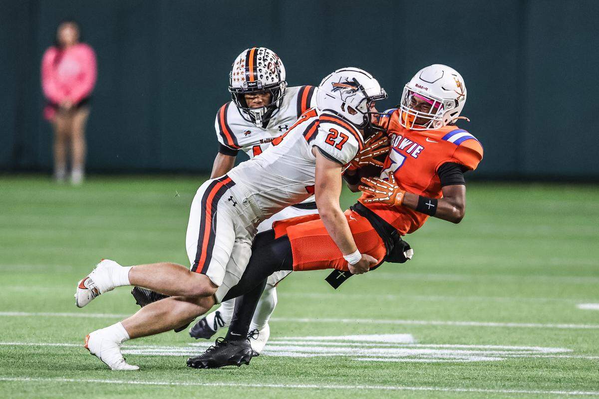Haltom linebacker Jaxon Cornue (27) tackles Arlington Bowie receiver Maxwell Nichols (7) on Thursday, Oct. 23, 2025, at Choctaw Stadium in Arlington.