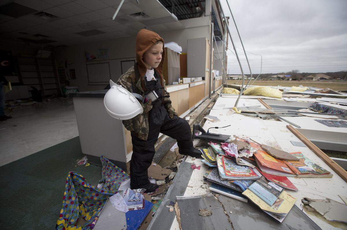 Jake Trice looks through the tornado-damaged rubble of his third-grade classroom at Donald T. Shields Elementary School in Glenn Heights, south of Dallas, on Monday, Dec. 28, 2015.  