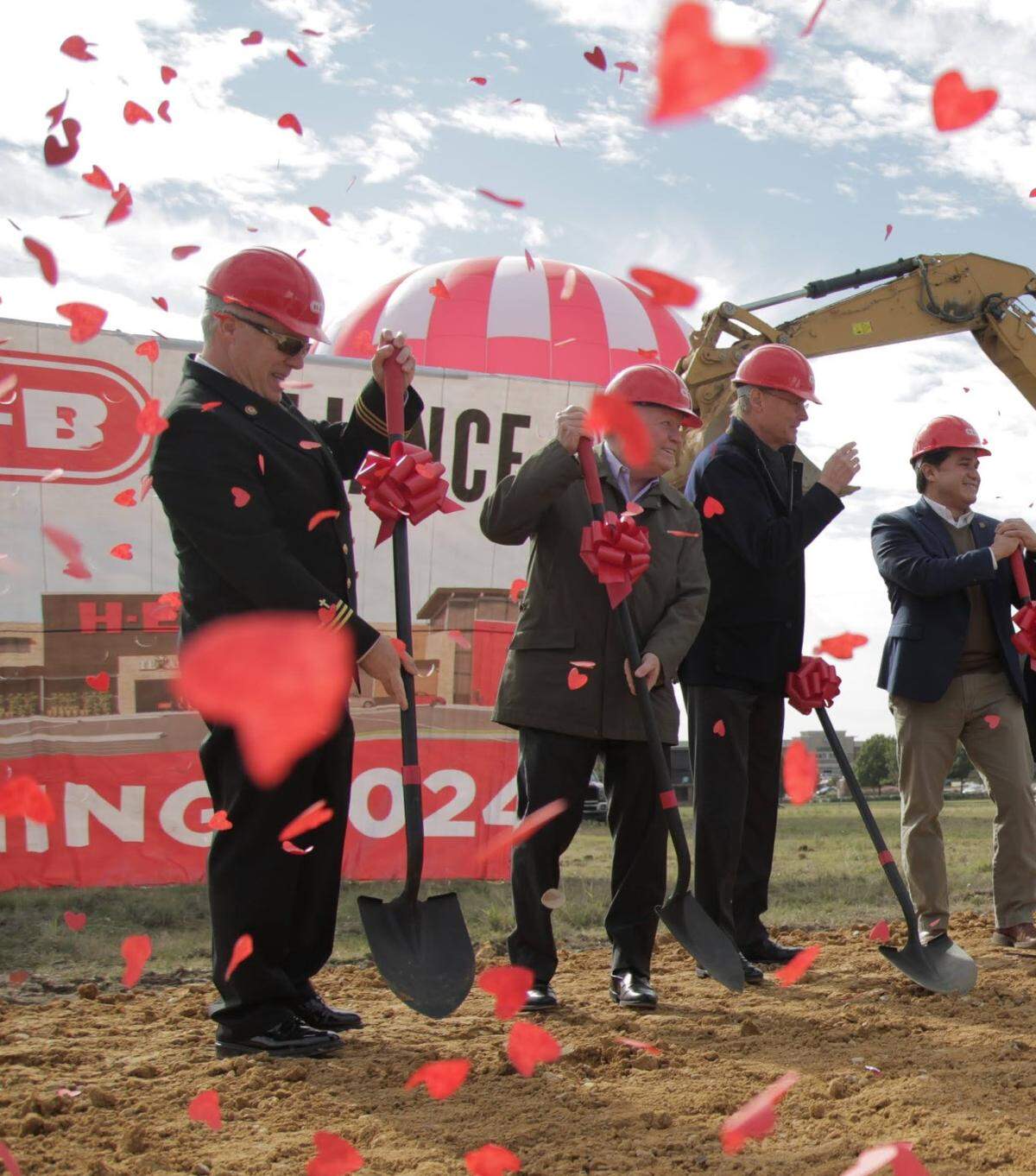 People wearing hard hats at a groundbreaking with confetti falling all around. 