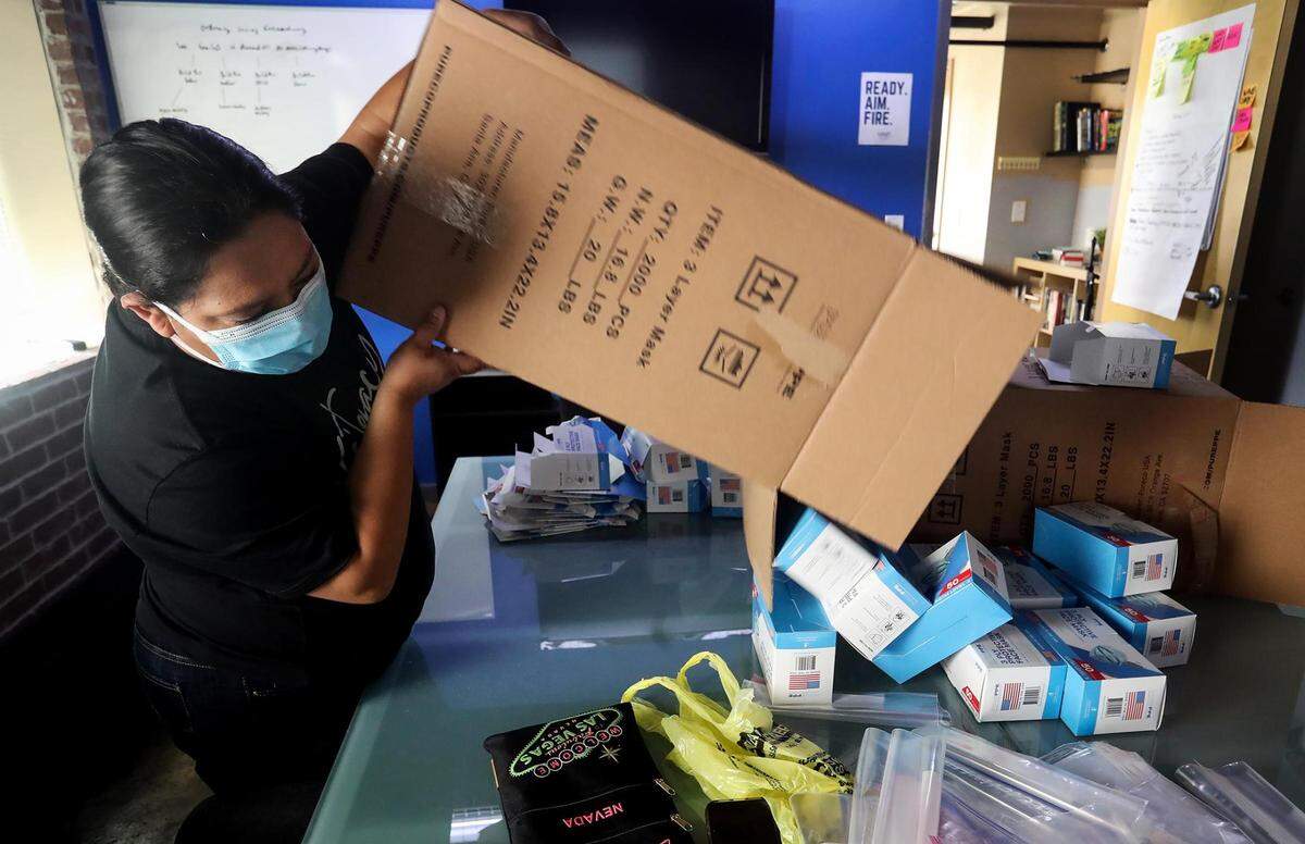 Roxanne Martinez dumps a box full of face masks onto the table while putting together personal protection kits for residents of her Diamond Hill in March 2021.