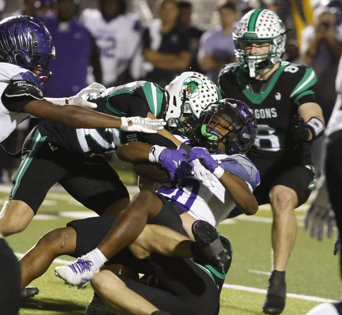 Southlake defensive backs Austin Bussmann (23) and Parker Harris (6) wrap up Crowley running back Kenyen Cotton (20) in the middle during the first half of a UIL Conference 6A D2 Bi-District playoff game between Crowley and Southlake Carroll at Dragon Stadium in Southlake, Texas, Thursday, Nov. 13, 2025.