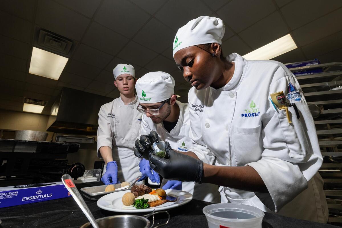 Culinary Arts students Kaden Hanson, left, Enrique Enriquiez, center, and Makayla Stephens work together to plate the Spinalis Roulade in a practice session at the practice kitchen in Ben Barber Innovation Academy at Mansfield on Friday, April 18, 2025.