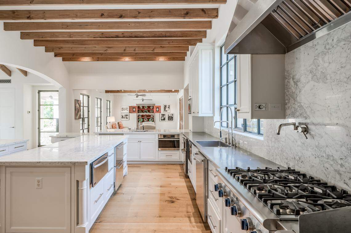The chef’s kitchen at the Houston home boasts Sub-Zero and Thermador appliances, marble and stainless countertops, exposed beams and a breakfast area overlooking the landscaped backyard.