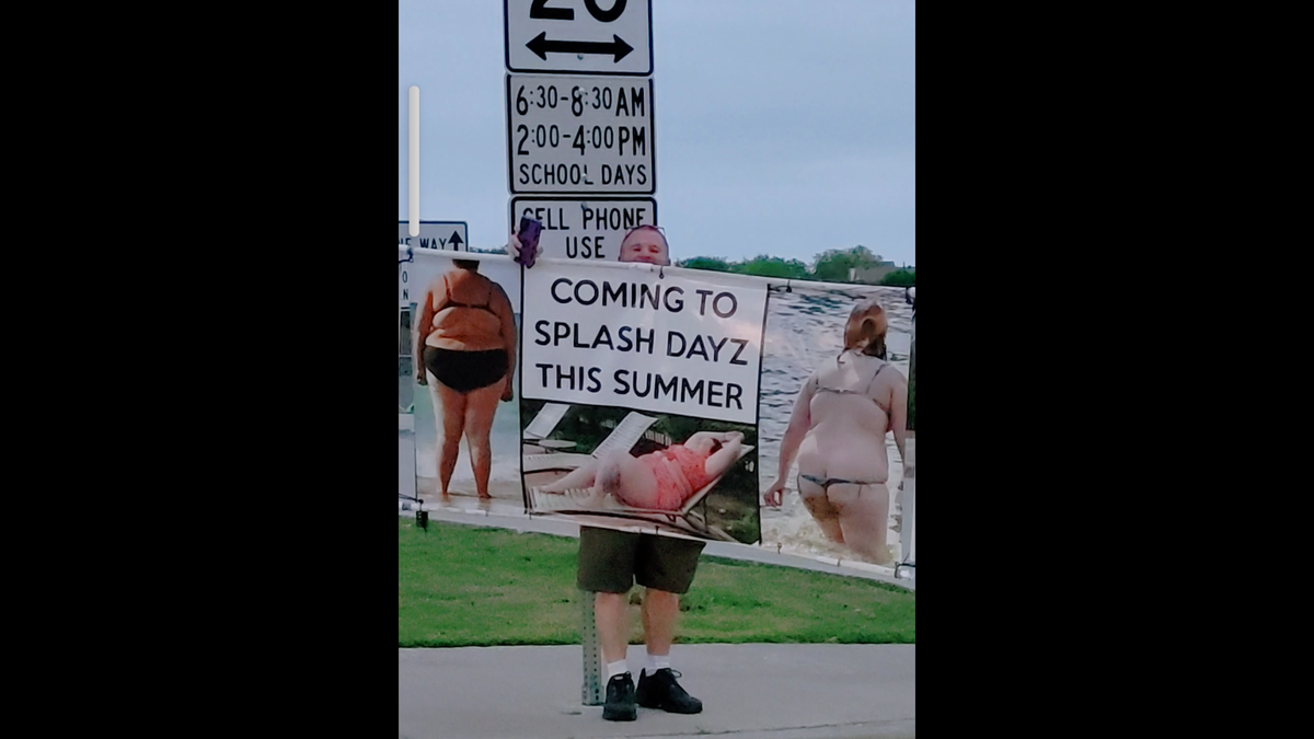 Scott Evans holding a large banner with three images of plus-size women in small bikinis with words that say "Coming to Splash Dayz This Summer"