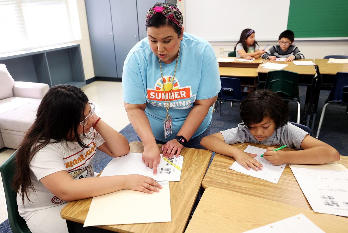 Alexandra Flores helps students while teaching third-grade math during summer learning at Rufino Mendoza Elementary School on June 12 in Fort Worth.