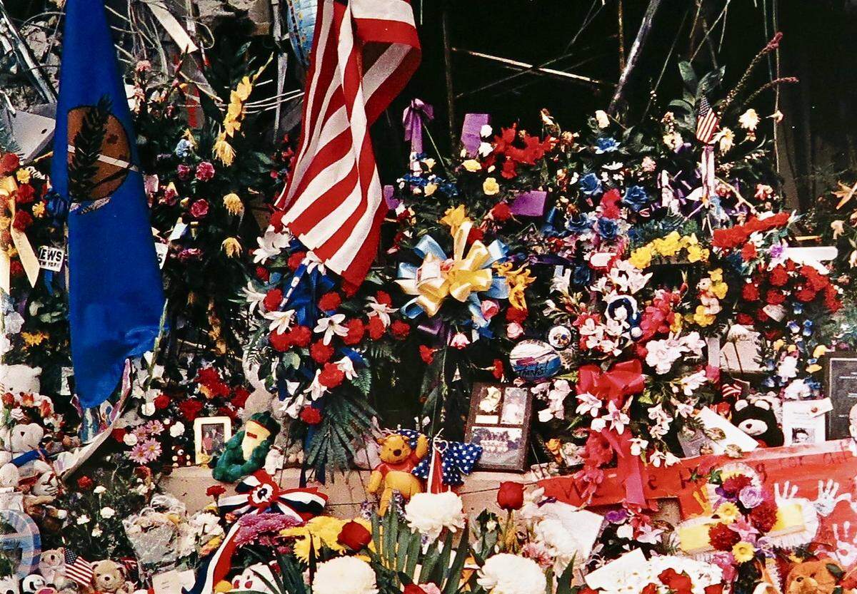 An outpouring of roses, wreaths, ribbons and stuffed animals. laid by rescue workers before a final memorial service, obscures the west end of the Murrah Federal Building in Oklahoma City, Oklahoma. This photo was from “Requiem For The Heartland, The Oklahoma City Bombing,” a book published to aid the victims and their families.