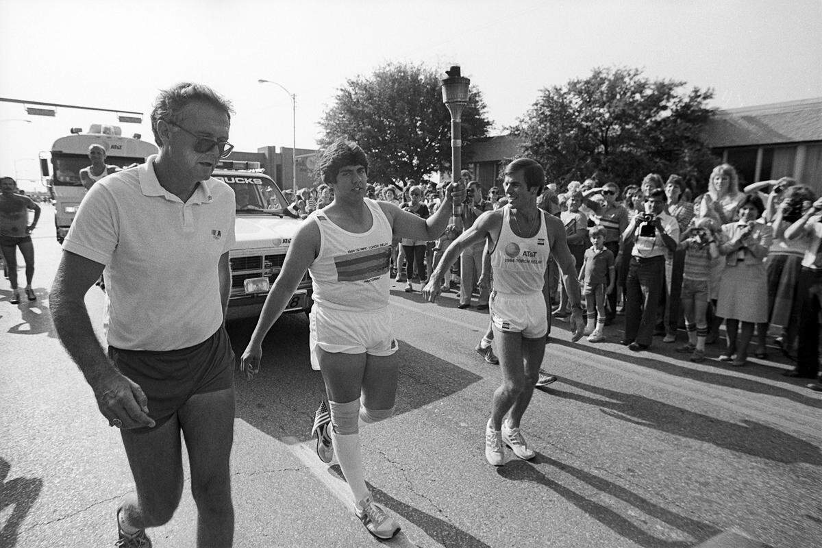 Olympic Torch relay team runner Kevin Procaccino, center, as he carries the torch as part of the 1984 Olympic Torch Relay in Arlington, Texas.