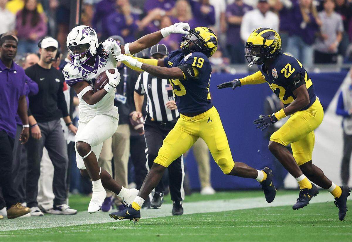 TCU running back Kendre Miller stiff arms a Michigan player during their game at the Vrbo Fiesta Bowl in Glendale, Ariz., on Saturday, December 31, 2022.