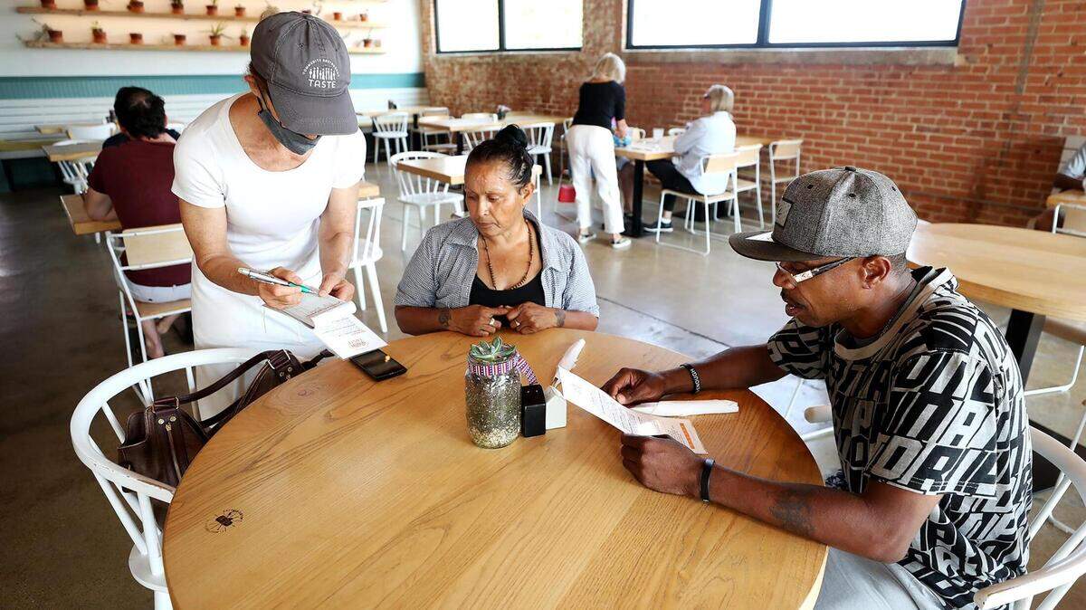 Volunteer Leslie Eades, left, takes Maria Tovar, center, and Kelvin WilliamsÕ order at Taste Project in Fort Worth on Wednesday, July 21, 2021. Taste Project is a nonprofit created to address food insecurity. The restaurant provides healthy food without a price tag, asking costumers to pay what they can afford.