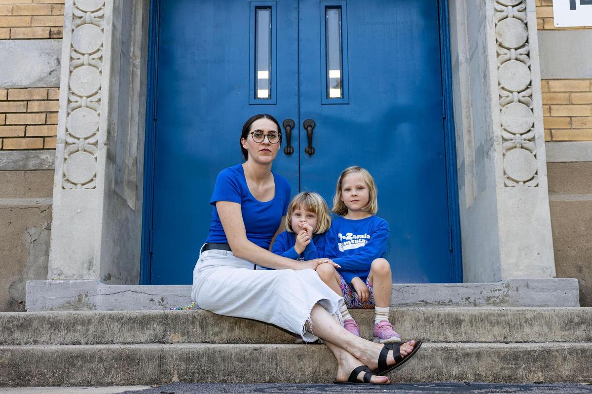 De Zavala parent Heather Tolksdorf is photographed with her twin daughters Sophia, middle, and Olivia, 5, right, on the door steps in front of De Zavala Elementary School in Fort Worth on June 13. De Zavala is one of 18 schools the district is scheduled to close and consolidate over the next four years. Located in Fort Worth’s Fairmount neighborhood, the school is in a part of the city where Fort Worth ISD has seen its enrollment dwindle over the past five years, even as the population of school-aged children has grown.