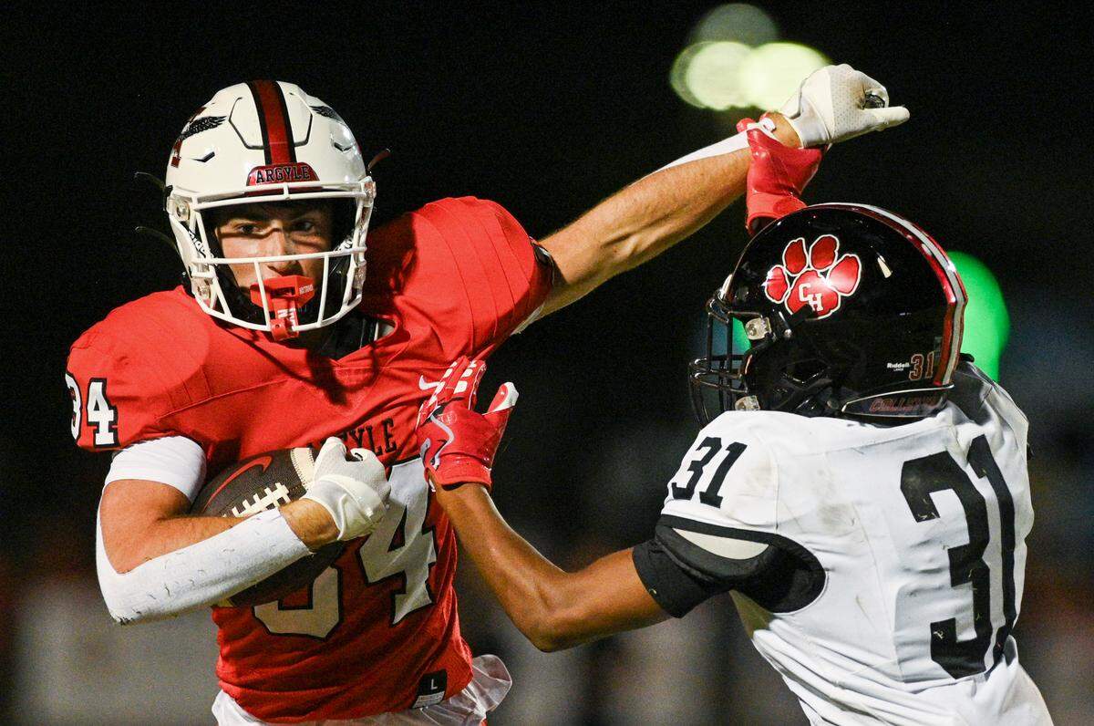 Argyle running back Logan Rexroat (34) fends off Colleyville Heritage defensive back Chase Gibson (31) during a UIL football game at Eagle Stadium in Argyle, Texas on Friday, Sept. 27, 2024.