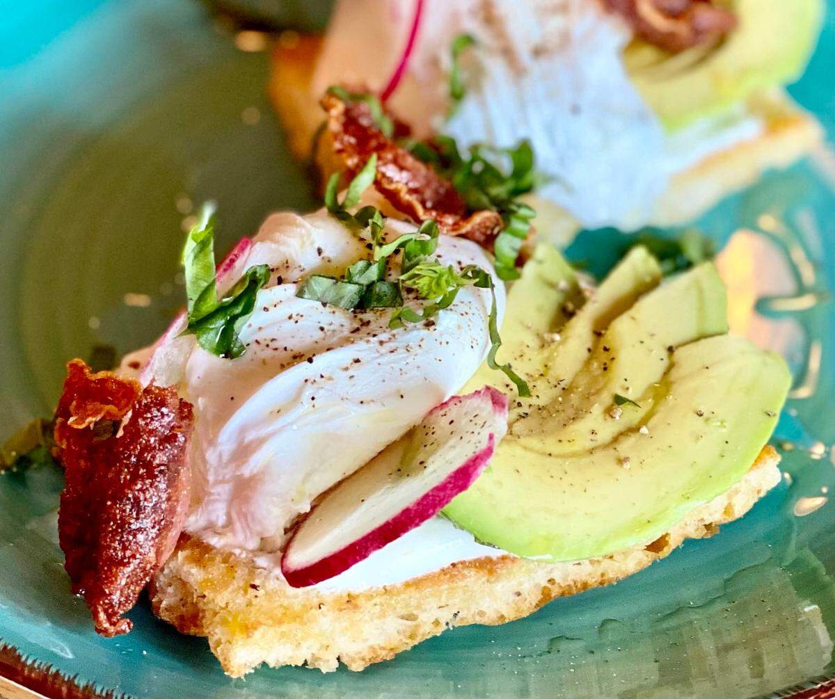 Avocado toast at Gemelle comes on focaccia with lemon yogurt, arugula, tomatoes, a poached egg and salami