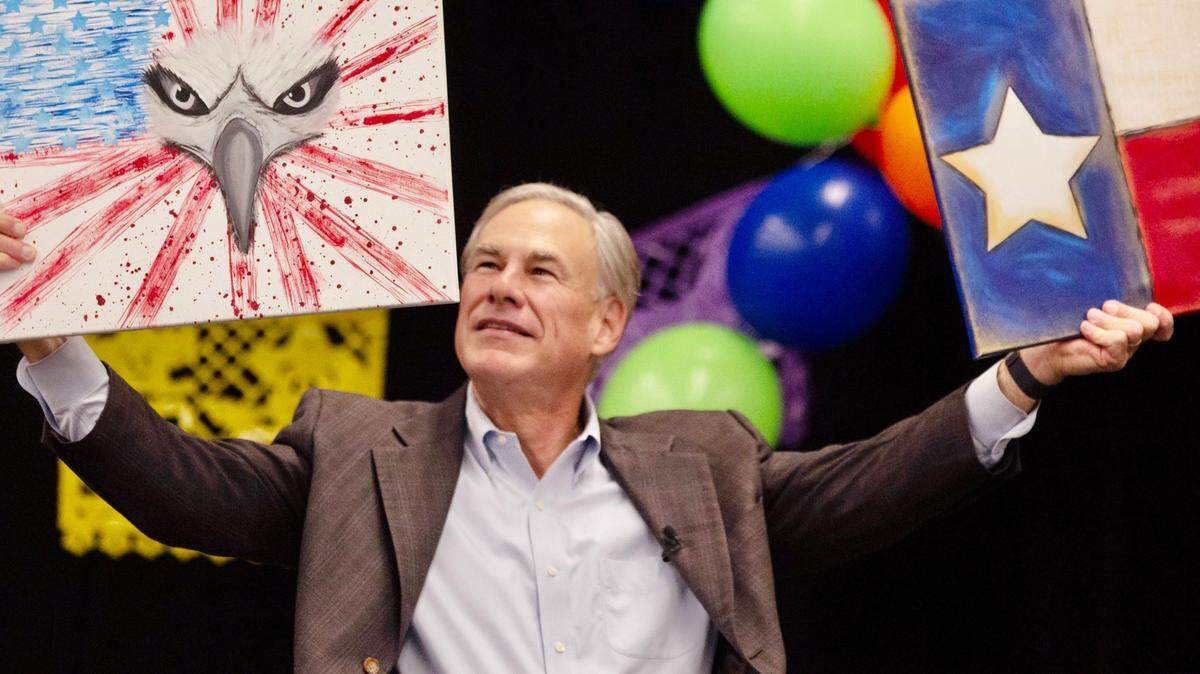 Gov. Greg Abbott holds up two paintings he received as a gift at the Midland Chapter of the Republican National Hispanic Assembly’s Reagan Lunch at the Bush Convention Center, Friday, Nov. 5, 2021, in Midland, Texas. (Jacob Ford/Odessa American via AP)