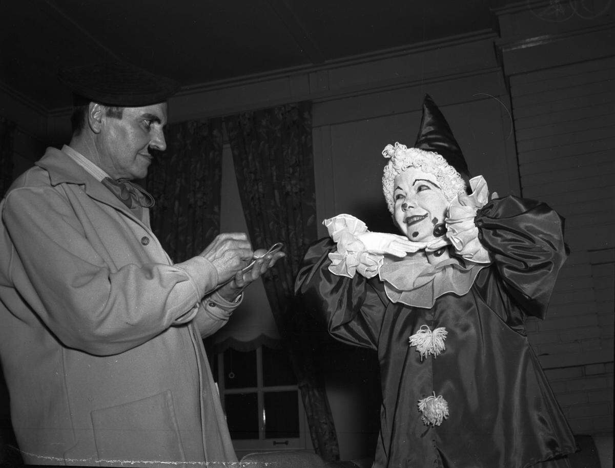 Mr. Beall is dressed in an artist costume wearing a berret, scarf, and trench coat drawing on a small pad. Mrs. Brown is wearing a clown costume, complete with the painted face, posing for the drawing.