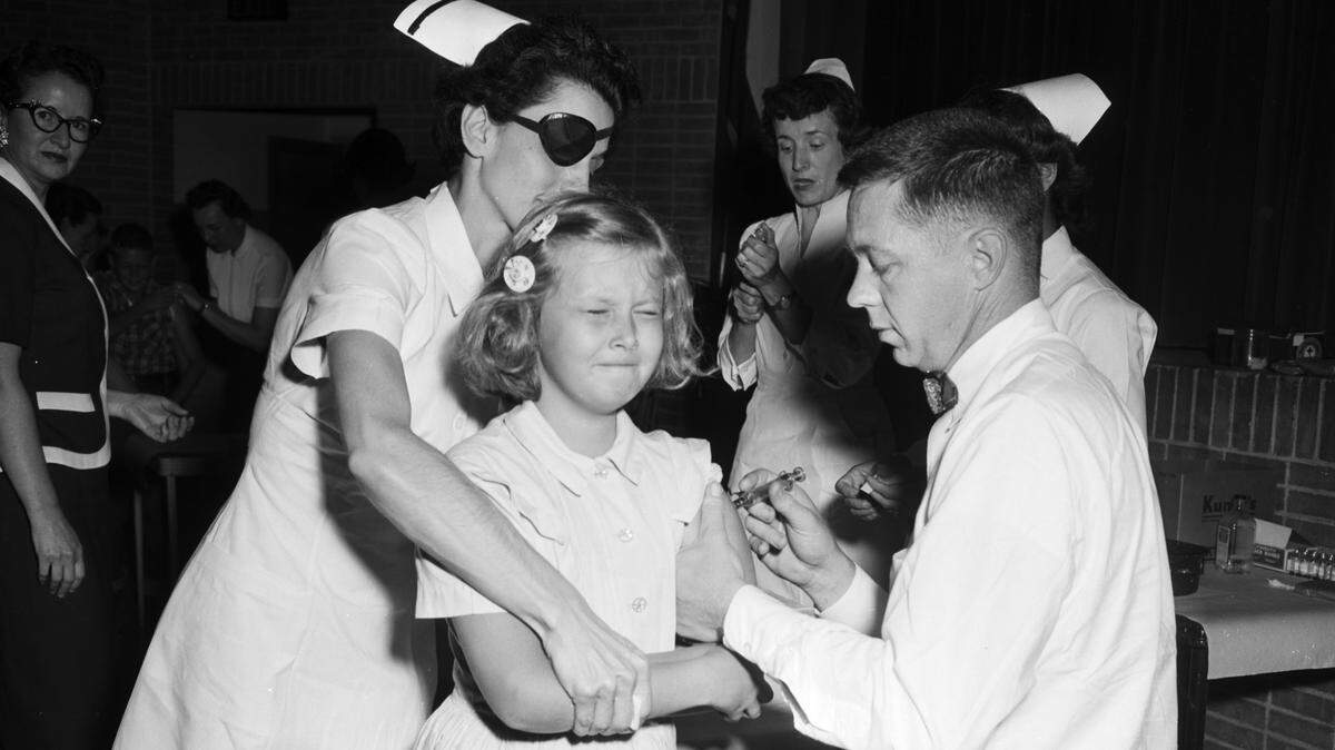 In this file photo taken April 8, 1955, Barbara Ellen Watson, 9 years old and a fourth-grader at West Side Elementary in Arlington, gets the first Salk polio vaccine given in Tarrant County. Dr. Frank Wallace is the physician, Mrs. D.S. Gerould is nurse.