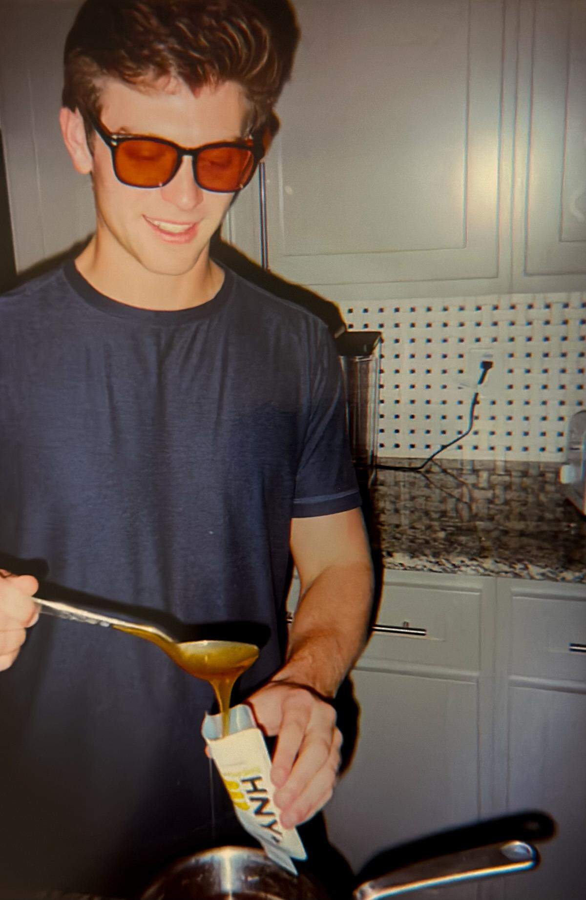 Ross Cooley spooning a honey and salt concoction into the first ever HNY+ packaging at his TCU college house in Fort Worth.