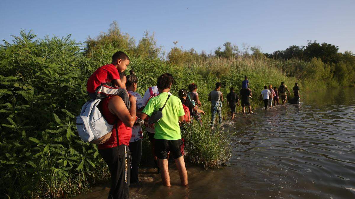 Migrants walk along an island in the middle of the Rio Grande as they make cross from Mexico into Eagle Pass, Texas on July 21. A federal judge threw out the Biden administration’s new immigration policy Tuesday, ruling that the revised rules for asylum-seekers were unlawful.