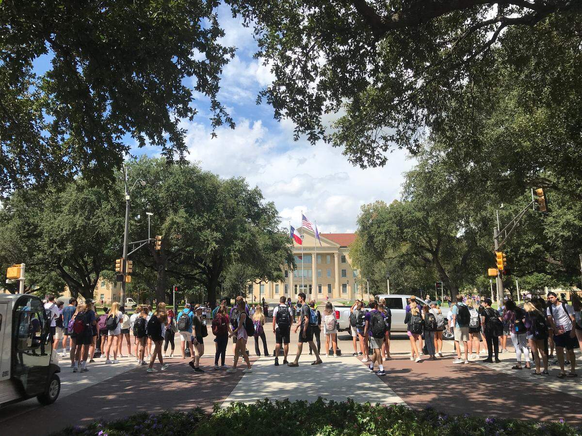Texas Christian University students wait for the OK from a TCU police officer to cross University Drive on Sept. 13. Prompted by two accidents that resulted in non-life-threatening injuries, the university is sending officers to crosswalks this year to help direct pedestrian foot traffic and vehicle traffic.