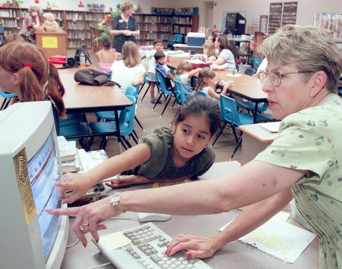 Aug. 29, 2000: Media coordinator Linda Honaker helps Anais Esquivel, 9, check out a book at the North Euless Elementary School Library. The library was closed due to construction during much of last year.