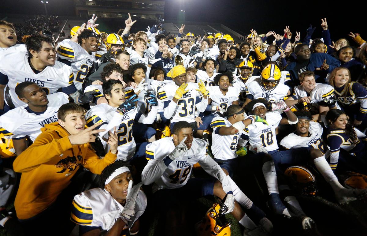 The Lamar Vikings celebrate their 37-34 victory over the Trinity Trojans with the bi-district trophy at midfield after Friday’s game at at Pennington Field in Bedford.