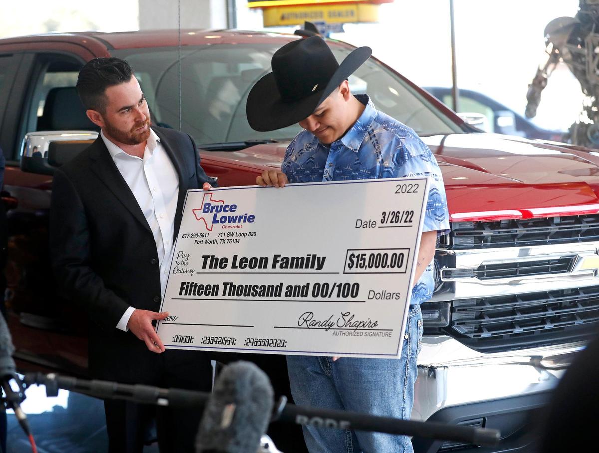 Bruce Lowrie Chevrolet Vice President Randall Shapiro gives a check for $15,000 to Riley Leon, 16, at Bruce Lowrie Chevrolet in Fort Worth, Texas, Saturday, March 26, 2022. Leon received a new Chevrolet Silverado after the one he was driving was totaled in a tornado.