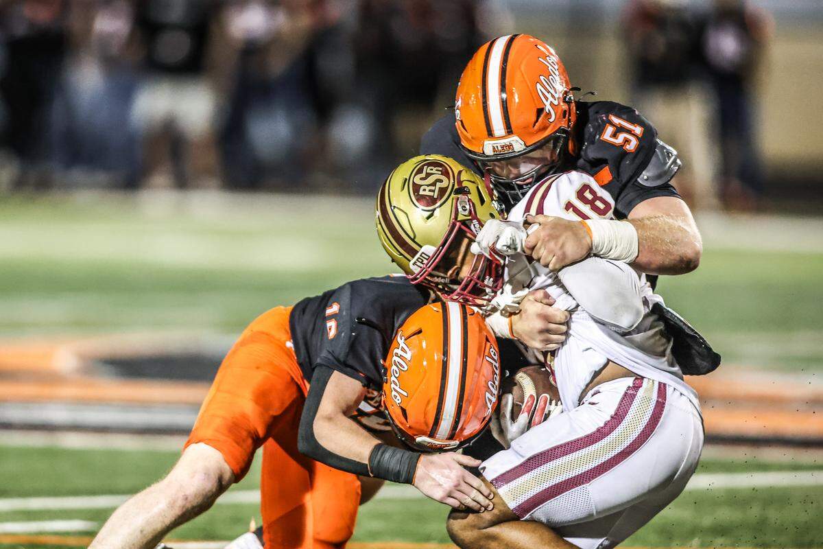 Saginaw’s Jahirim Skinner (18) is tackled by Aledo’s Cole Cox (16) and Decker Sanders (51) in a Class 5A Division I bi-district playoff game on Thursday, November 13, 2025 at Tim Buchanan Stadium in Aledo, Texas.