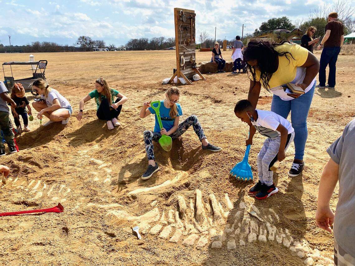 Kids and adults digging at a replica prehistoric site at a previous event