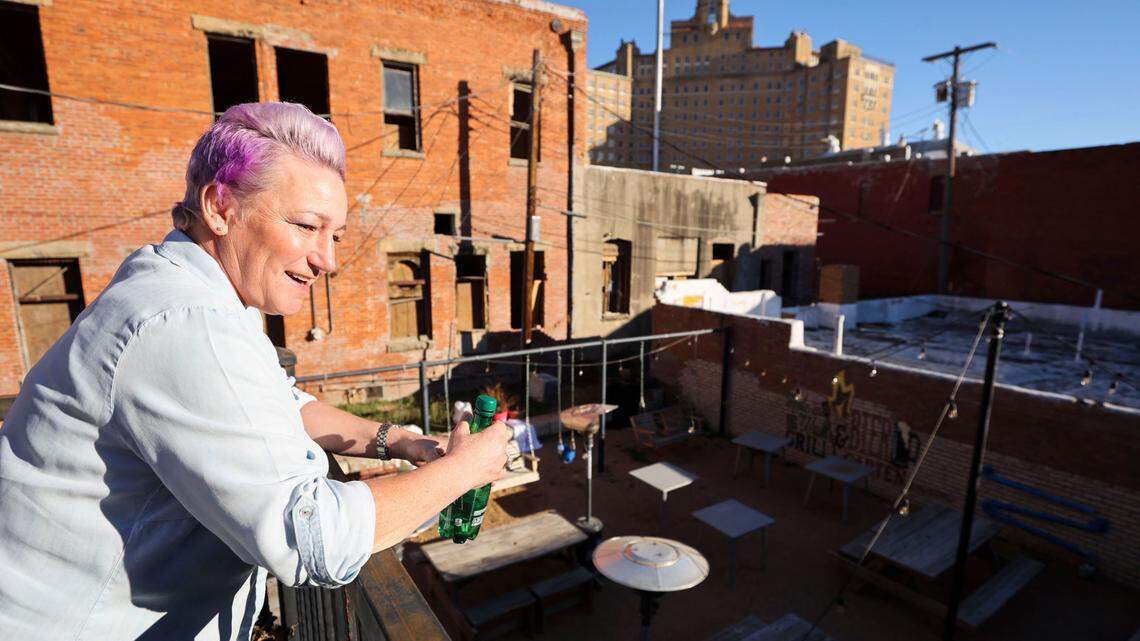 Perri Leavelle stands on the balcony of Lofts & Hospitality to look over Hole in the Wall below and the Baker Hotel in the background in Mineral Wells.