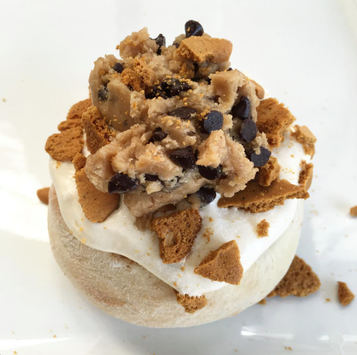 A Cinnaholic cinnamon roll with chai frosting, topped with ginger snaps and chocolate-chip cookie dough.