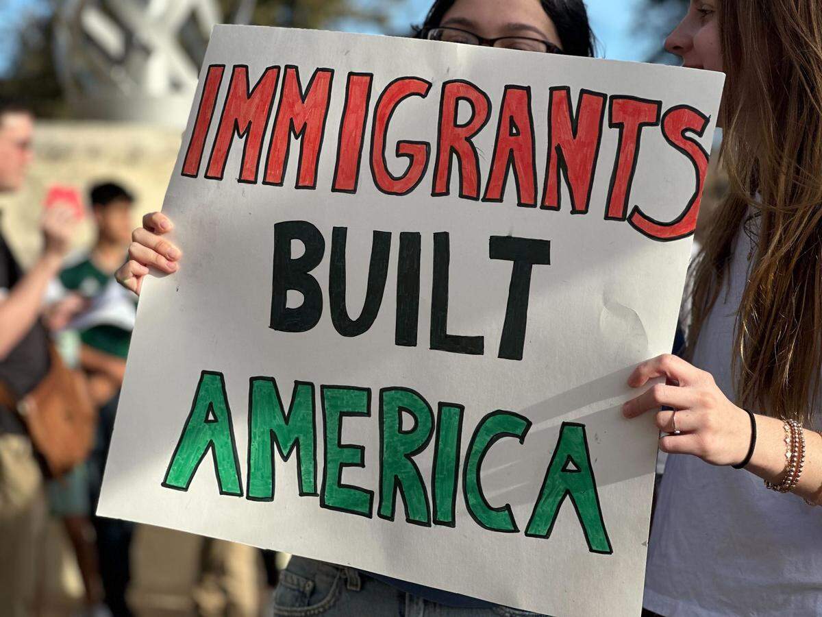 Community members from Tarrant County hold posters to voice their opinions against mass deportation and ICE raids outside Arlington City Hall on Sunday.