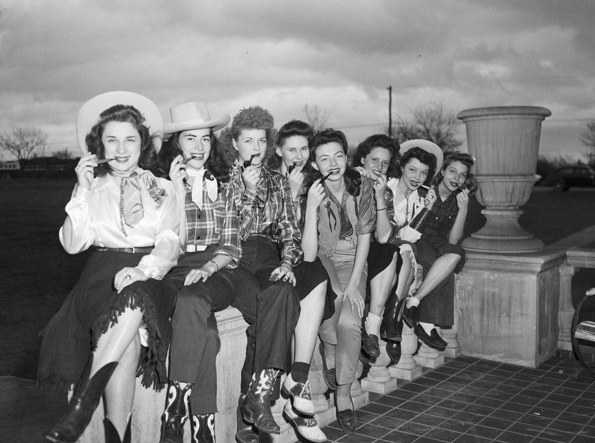 Feb. 16, 1945: TCU students smoke pipes as they sit on a railing during Ranch Week. The students are, left to right, Alice Ann Ward of Houston; Carolyn McCartney of Waxahachie; Ruth Rawlls of Weatherford; Patricia Ward of Mount Pleasant; Jean Carol McCullough of Dallas; Frances Leak of Longview; Margaret Ann Lowrey of Shawnee, Okla.; and Elizabeth Davis of Dallas.